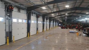 The inside of a warehouse with a long row of commercial garage doors.