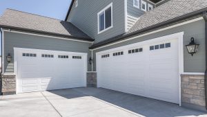 A beautiful home with grey siding and two large garages.